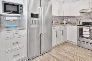 una nevera de acero inoxidable en una cocina con armarios blancos en Beach Cottage 1205 en Clearwater Beach