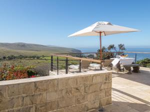 a patio with an umbrella and a table and chairs at Castle On The Heads in Knysna