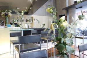 a restaurant with black chairs and a bar with yellow roses at Hotel Madanis in Barcelona