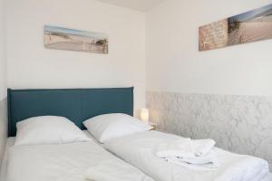 - une chambre avec 2 lits avec des draps blancs et une tête de lit verte dans l'établissement Villa am Meer Pier 52, à Grömitz