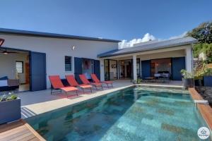 ein Haus mit einem Pool und roten Stühlen in der Unterkunft Villa Aïna - Piscine 4 étoiles - Vue mer - Saint Leu in Saint-Leu