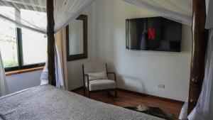 1 dormitorio con 1 cama, 1 silla y TV en The Cabin en Nakuru