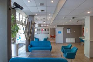eine Lobby mit blauen Sofas und Stühlen in einem Gebäude in der Unterkunft CYAN HOTEL - Roissy Villepinte Parc des Expositions in Roissy-en-France