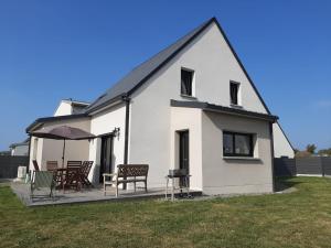 una casa bianca con patio con sedie e ombrellone di Paul Emile Victor a Saint-Aubin-des-Préaux