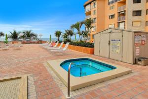 a swimming pool with chairs and a building at Beach Cottage 2202 in Clearwater Beach