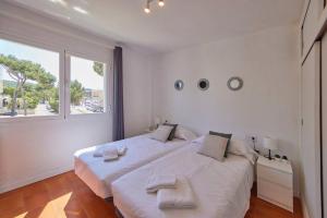 a white bedroom with a large bed with two white towels at Nura Houses Duplex Magaluf 2 in Magaluf