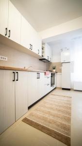 an empty kitchen with white cabinets and a rug at Ballade Apartment in Iaşi