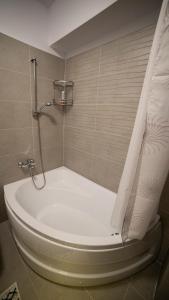 a bath tub with a shower curtain in a bathroom at Ballade Apartment in Iaşi