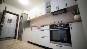 a kitchen with white cabinets and a black oven at Ballade Apartment in Iaşi