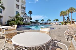 een witte tafel en stoelen naast een zwembad bij Beach Palms 108 in Clearwater Beach