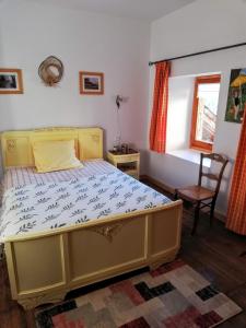 um quarto com uma cama, uma cadeira e uma janela em maison immersion hautes alpes em Freissinieres