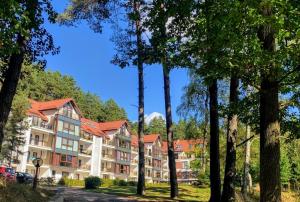 duży budynek z drzewami na pierwszym planie w obiekcie Apartament Perła nr 19 nad Jeziorem Pluszne w mieście Mierki