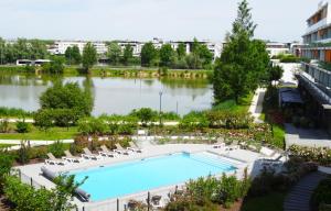 an overhead view of a swimming pool with chairs and a lake at Appart-Hôtel Mer & Golf City Bordeaux - Bruges in Bruges
