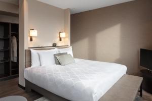 ein Schlafzimmer mit einem großen weißen Bett und einem TV in der Unterkunft Hotel Victoria in Basel