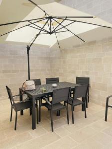 a black table and chairs with a white umbrella at La Caletta Suite Torre Canne in Torre Canne