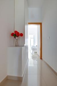 Habitación blanca con un jarrón de flores rojas en la pared en Prime Location Apartment with Side Seaviews, en Sliema