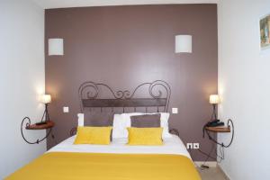 a bedroom with a large bed with two yellow pillows at Hotel Restaurant Le Gardon - Pont du Gard in Collias