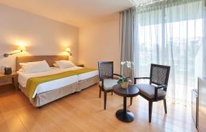 a hotel room with a bed and a table and chairs at Golden Residence Hotel in Funchal