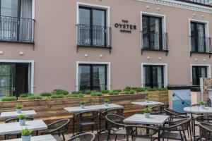 un patio al aire libre con mesas y sillas frente a un edificio en Oyster House, en Mumbles