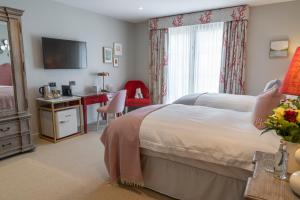 ザ・マンブルズにあるOyster Houseのベッドと机とテレビのある寝室