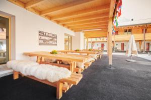a row of wooden tables and benches with a umbrella at Reka-Ferienanlage Scuol in Scuol +15 photos