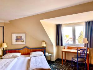 a hotel room with a bed and a desk at Country Hotel Timmendorfer Strand in Timmendorfer Strand