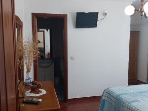 a bedroom with a bed and a table with a tv on the wall at Casa do Eido in Geres