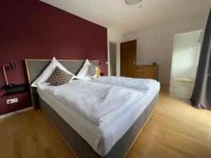 um quarto com uma cama grande com lençóis brancos e almofadas em Alpenperle Hochfeld em Tegernsee