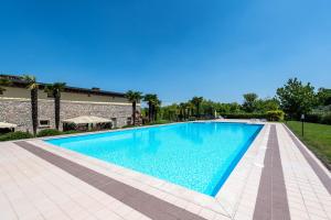 a swimming pool with blue water in front of a building at Garda Paradise Country House in Lonato del Garda