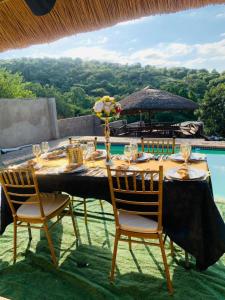 a table with wine glasses and chairs next to a pool at Siyaya’s Guest Palace in Jozini