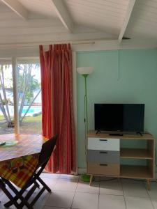 ein Wohnzimmer mit einem Tisch und einem TV in der Unterkunft Résidence Naturelle pour Naturistes in Le Moule