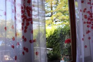 Una ventana con cortinas blancas con flores rojas. en Villetta sul mare, en Acquedolci