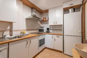 Una cocina con gabinetes blancos y un refrigerador de acero inoxidable. en Marina Esuri by Ĥ - Costa Esuri EEHM123P169, en Ayamonte