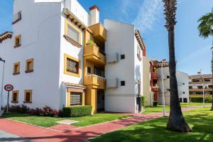 un edificio blanco con toques amarillos y una palmera en Marina Esuri by Ĥ - Costa Esuri EEHM123P169, en Ayamonte