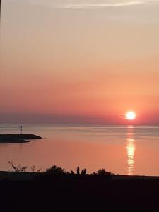 a sunset over the water with the sun in the sky at La Casa di Zorbas in Cariati +2 photos