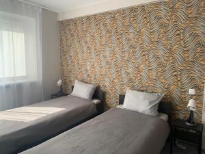 a room with two beds and a wall with a wallpaper at Hotel Marijampole in Marijampolė