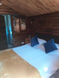 a bedroom with a large bed with blue pillows at Delightful cosy cabin in Margate