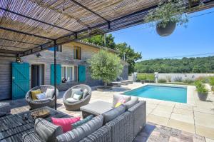 a patio with a couch and chairs and a pool at Le chant du coquelicot in Baziège
