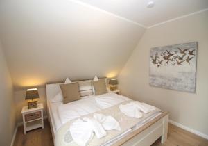 Schlafzimmer mit einem Bett mit weißer Bettwäsche und Kissen in der Unterkunft Beach House Reetdachhaus Beach House 2 in Tating