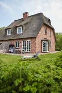 a house with a bench in front of it at Beach House Reetdachhaus Beach House 2 in Tating