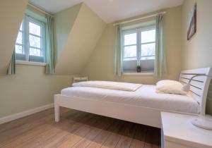 ein Schlafzimmer mit einem Bett und zwei Fenstern in der Unterkunft Reetdachhaus ASK EMBLA Reetdachhaus ASK in Sankt Peter-Ording