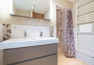 ein Badezimmer mit einem weißen Waschbecken und einer Dusche in der Unterkunft Reetdachhaus ASK EMBLA Reetdachhaus ASK in Sankt Peter-Ording + 26 Fotos