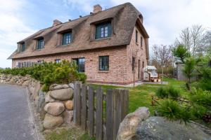 ein großes Backsteinhaus mit Dach in der Unterkunft Reetdachhaus ASK EMBLA Reetdachhaus ASK in Sankt Peter-Ording