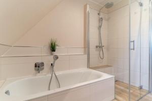 a white bathroom with a shower and a tub at Reetdachhaus Boy's Huus Reetdachhaus Boy's Huus 5a in Sankt Peter-Ording +25 photos