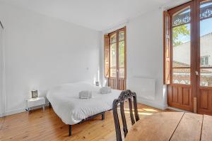 - une chambre blanche avec un lit et une table dans l'établissement LE MERCIER - Grand T4 de 100m2 en plein coeur de Toulouse, à Toulouse