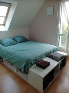 een slaapkamer met een bed met een groen dekbed bij Maison familiale sur la CÔTE D’ÉMERAUDE in Lancieux