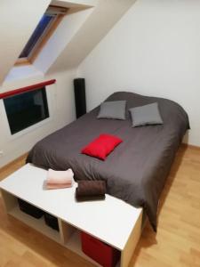 - une chambre avec un grand lit et des oreillers rouges dans l'établissement Maison familiale sur la CÔTE D’ÉMERAUDE, à Lancieux