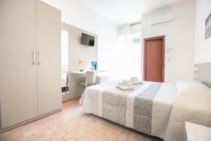 a white bedroom with a bed and a bathroom at Hotel Mara in Rimini