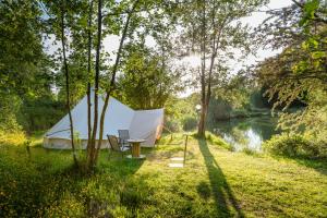 a tent and a table next to a river at Lloyds Meadow Glamping in Chester