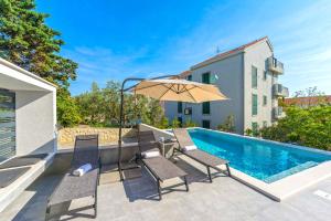 a patio with chairs and an umbrella next to a swimming pool at Summer Breeze Pool Apartments in Novalja